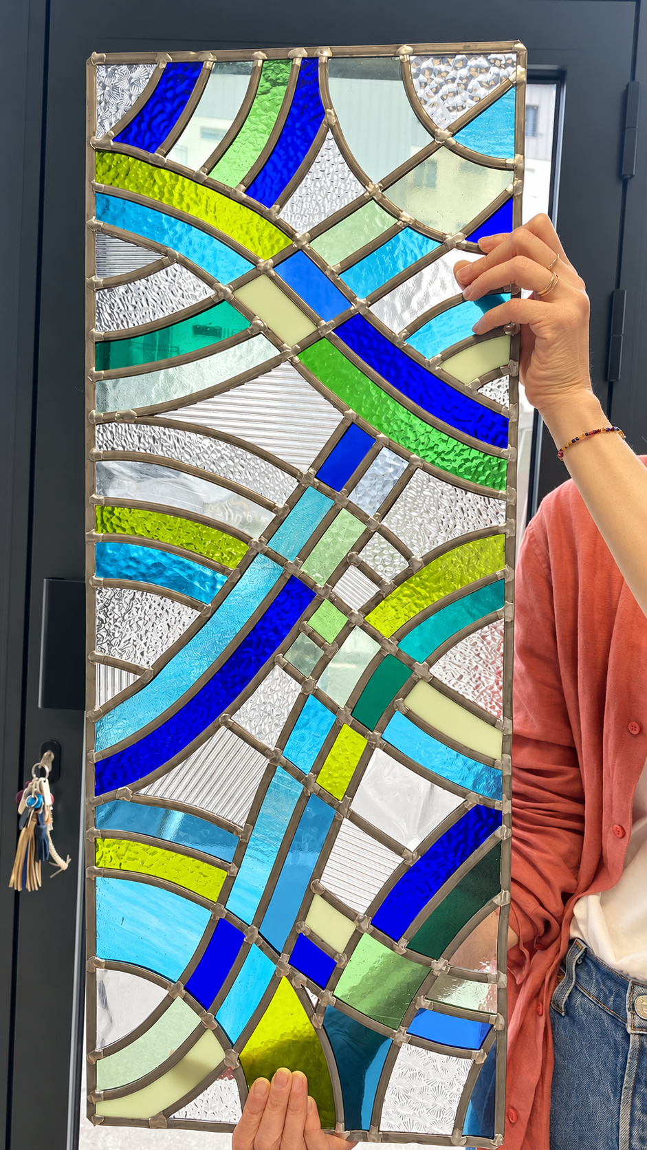 Grand vitrail abstrait composé de lignes entrecroisées et de verres bleus, verts et incolores