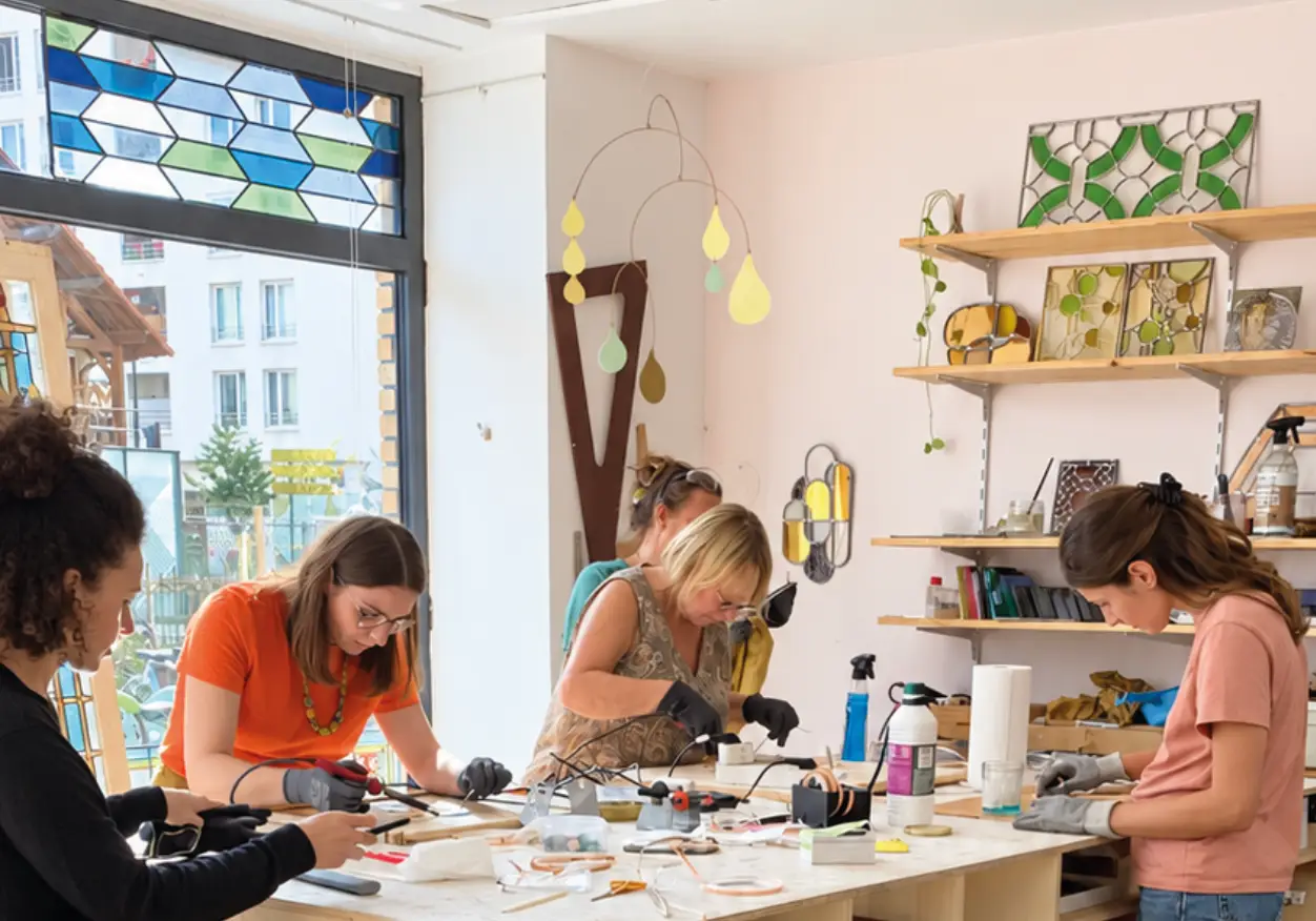 Élèves travaillant autour de la table pendant un cours de vitrail à l’Atelier Cocoroca